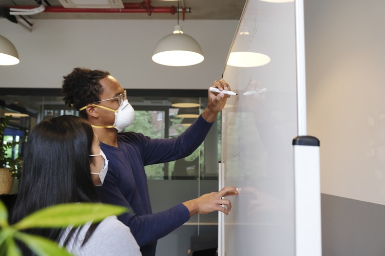 two people working on white board